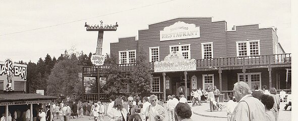 Viel Trubel herrscht vor dem Saloon auf dem Schwarz-Weiß-Bild aus alten Zeiten.