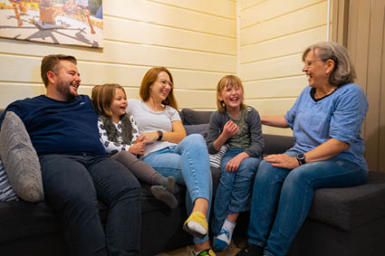 Nach einem aufregenden Tag im Freizeitpark sitzt die Familie gemütlich zusammen in der Family Plus Hütte auf einer Couch.