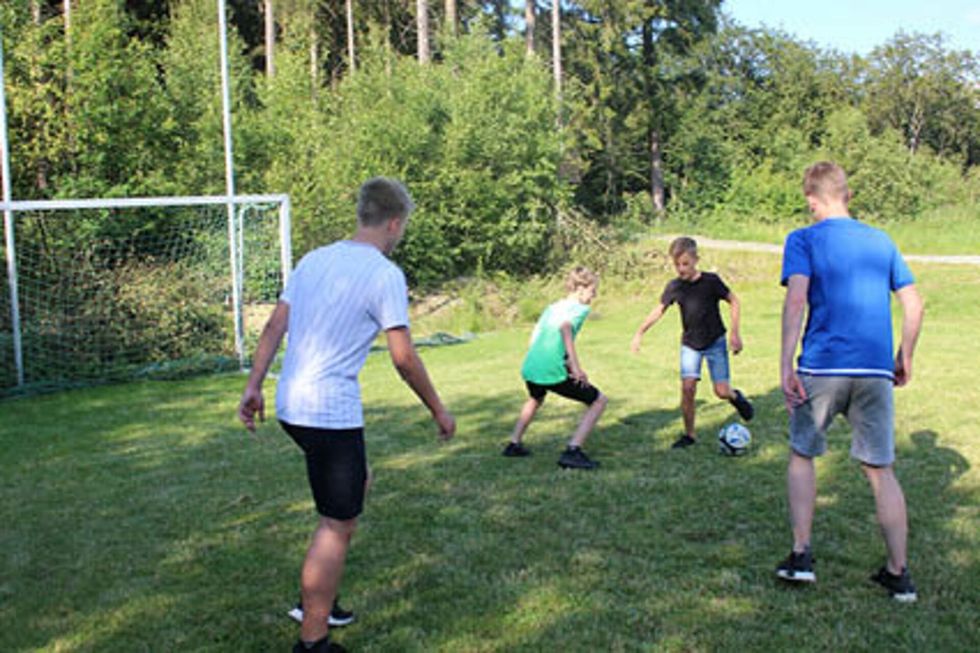 Auf dem Bolzplatz am Abenteuercamp spielen die Kinder nach dem Freizeitpark-Besuch am Abend Fußball.