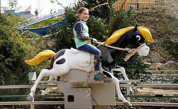 Mit der Pferdereitbahn Kleiner Donners wilder Ritt hat das Mädchen viel Spaß.