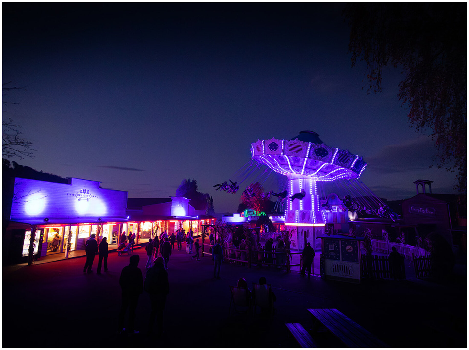 Der Wellenflieger beleuchtet im Dunkeln mit vielen Gästen davor.