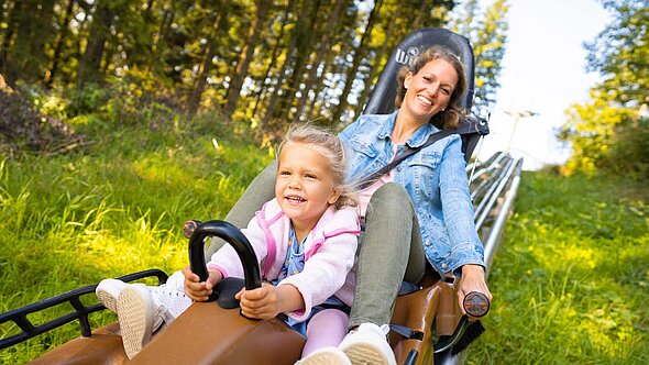 Die Tochter zeigt der Mama wie man mit der Sommerrodelbahn im FORT FUN unterwegs ist.