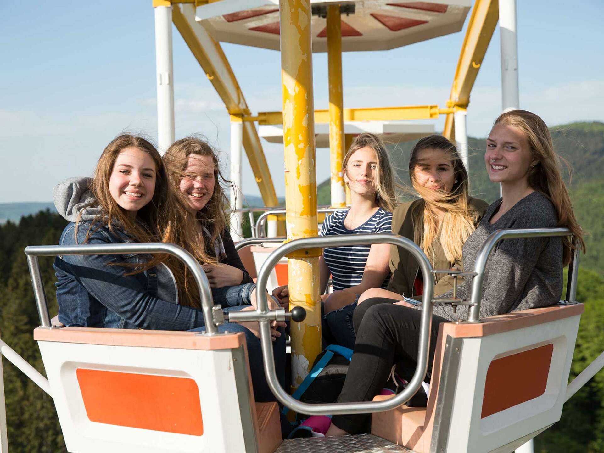 Fünf Mädchen einer Schulklasse sitzen im Riesenrad und haben Spaß.