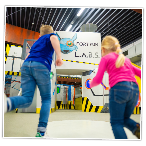 Zwei Kinder laufen in den Indoor-Spielplatz LABS im FORT FUN Abenteuerland.